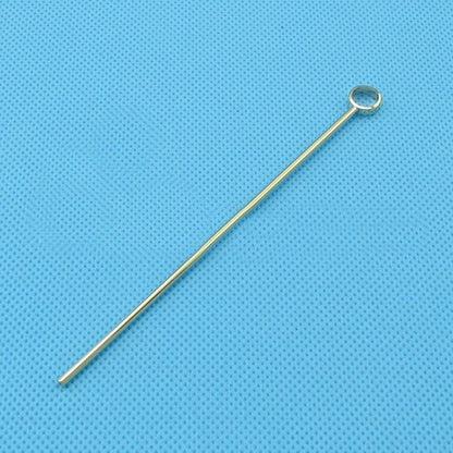 Gold-colored eye pin for jewelry making on blue textured background