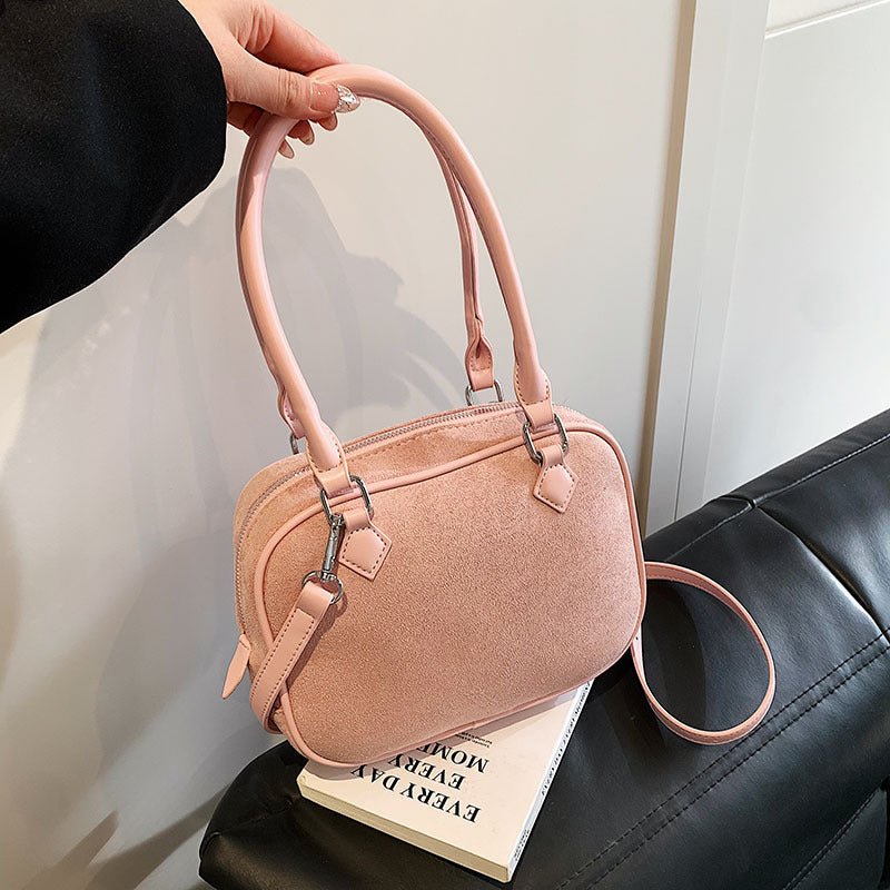 Pink suede handbag with top handle and shoulder strap, stylish women's fashion accessory