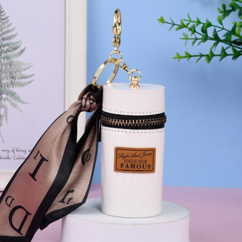 Glitter white keychain with gold zipper, 'Vogue New Famous' patch, and sheer ribbon, stylish fashion accessory