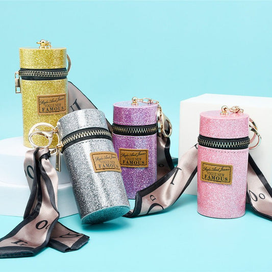 Glittery cylindrical keychain pouches in gold, silver, pink, purple with ribbon straps and zippers