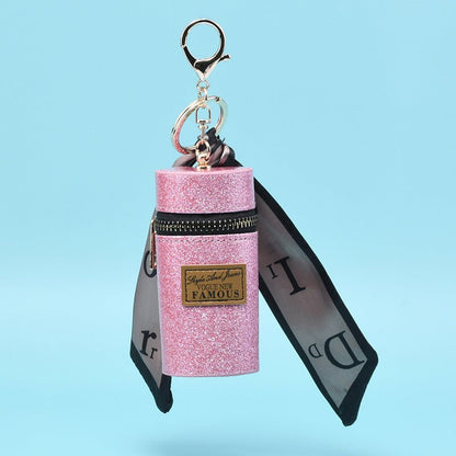 Pink glitter keychain pouch with ribbon, zipper, and 'Famous' label, fashion accessory for bags or keys