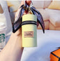 Pastel yellow keychain pouch with 'Vogue New Famous' label, silk ribbon, and zipper, held in hand near coffee cup