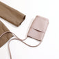Pink textured crossbody bag with long strap, paired with beige pants, minimalist fashion accessory
