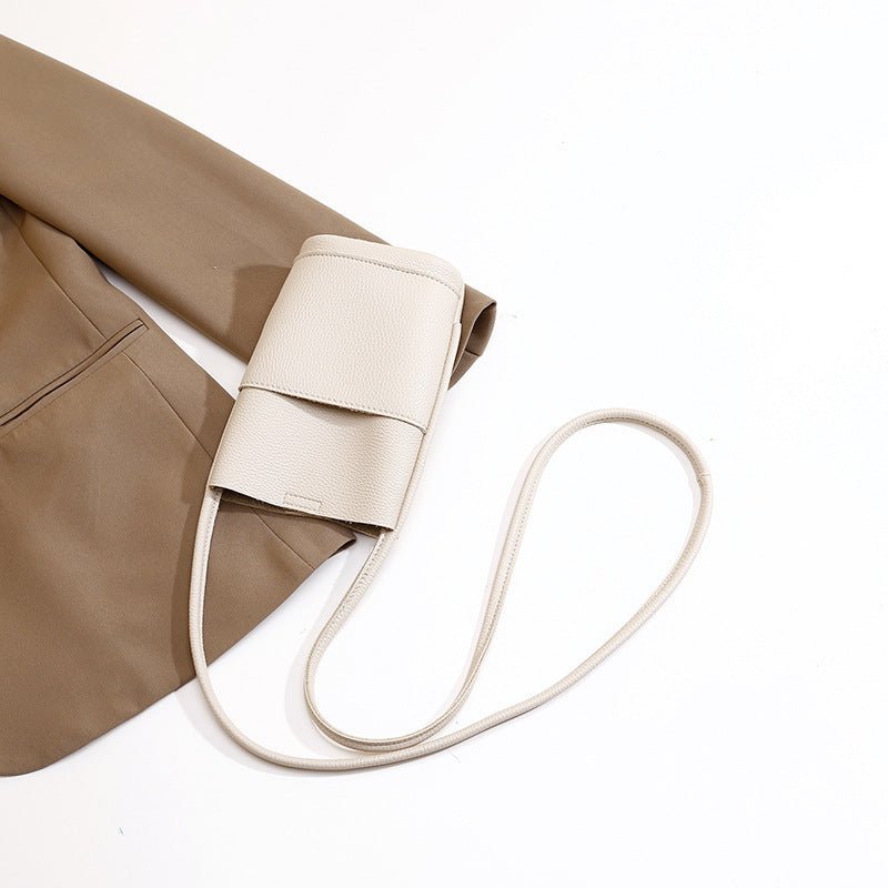 Cream mini crossbody bag with long strap, styled with beige blazer for chic fashion look
