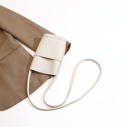 Cream mini crossbody bag with long strap, styled with beige blazer for chic fashion look