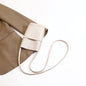 Cream mini crossbody bag with long strap, styled with beige blazer for chic fashion look