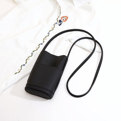 Black textured crossbody bag with long strap, styled with embroidered white shirt