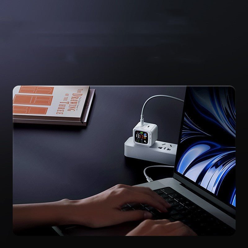 Smart digital power strip charging laptop and watch on dark desk with book nearby