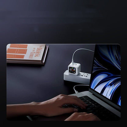 Smart digital power strip charging laptop and watch on dark desk with book nearby