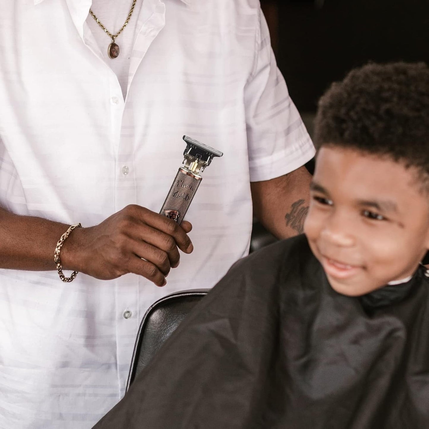 Barber holding electric hair clipper for kids' haircut, salon styling tool